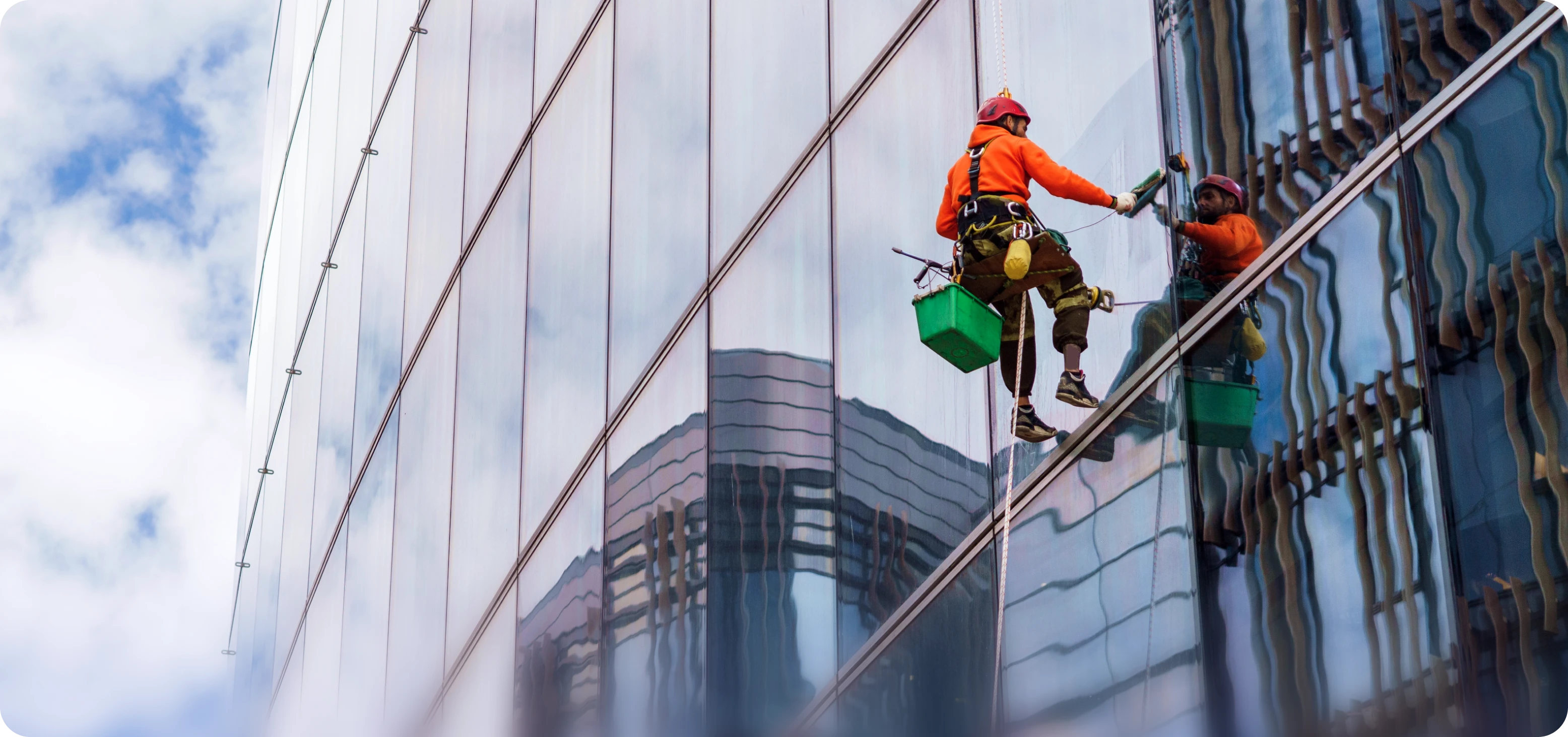 Graphic showing a window washer in an orange jacket and safety harness cleaning the high-rise glass windows of a modern skyscraper.