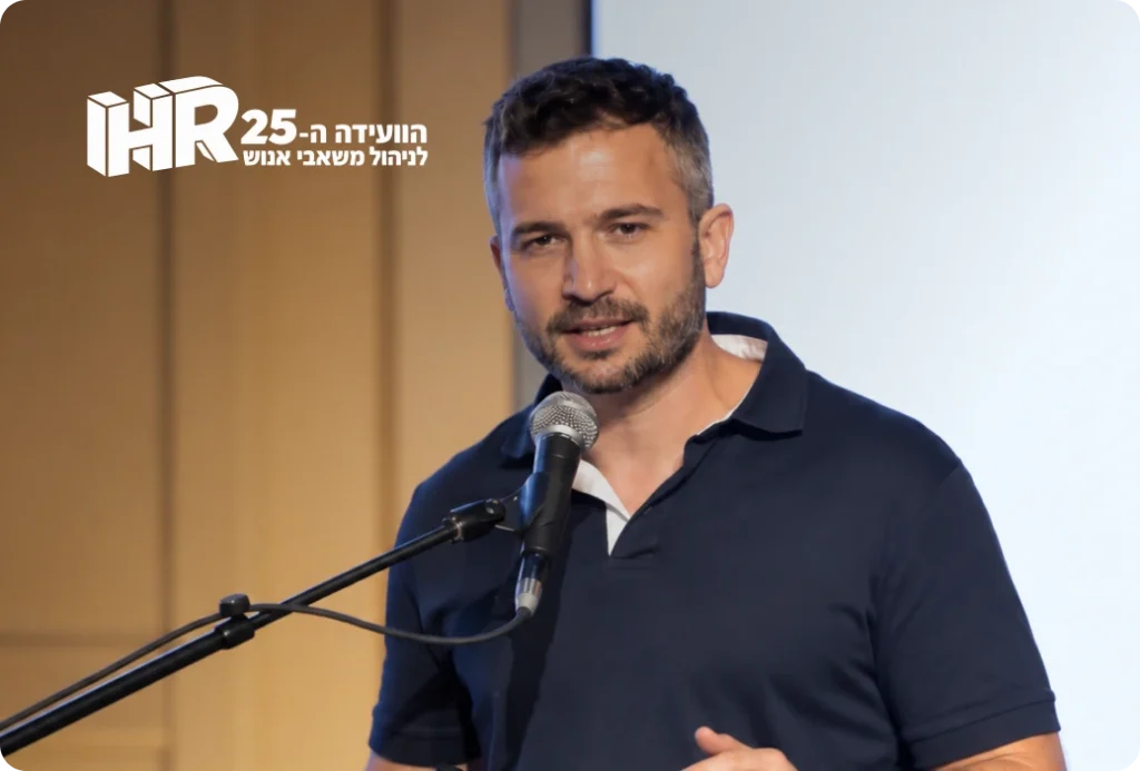 גבר נואם מול מיקרופון בכנס, עם לוגו "הוועידה ה-25 לניהול משאבי אנוש" HR25.