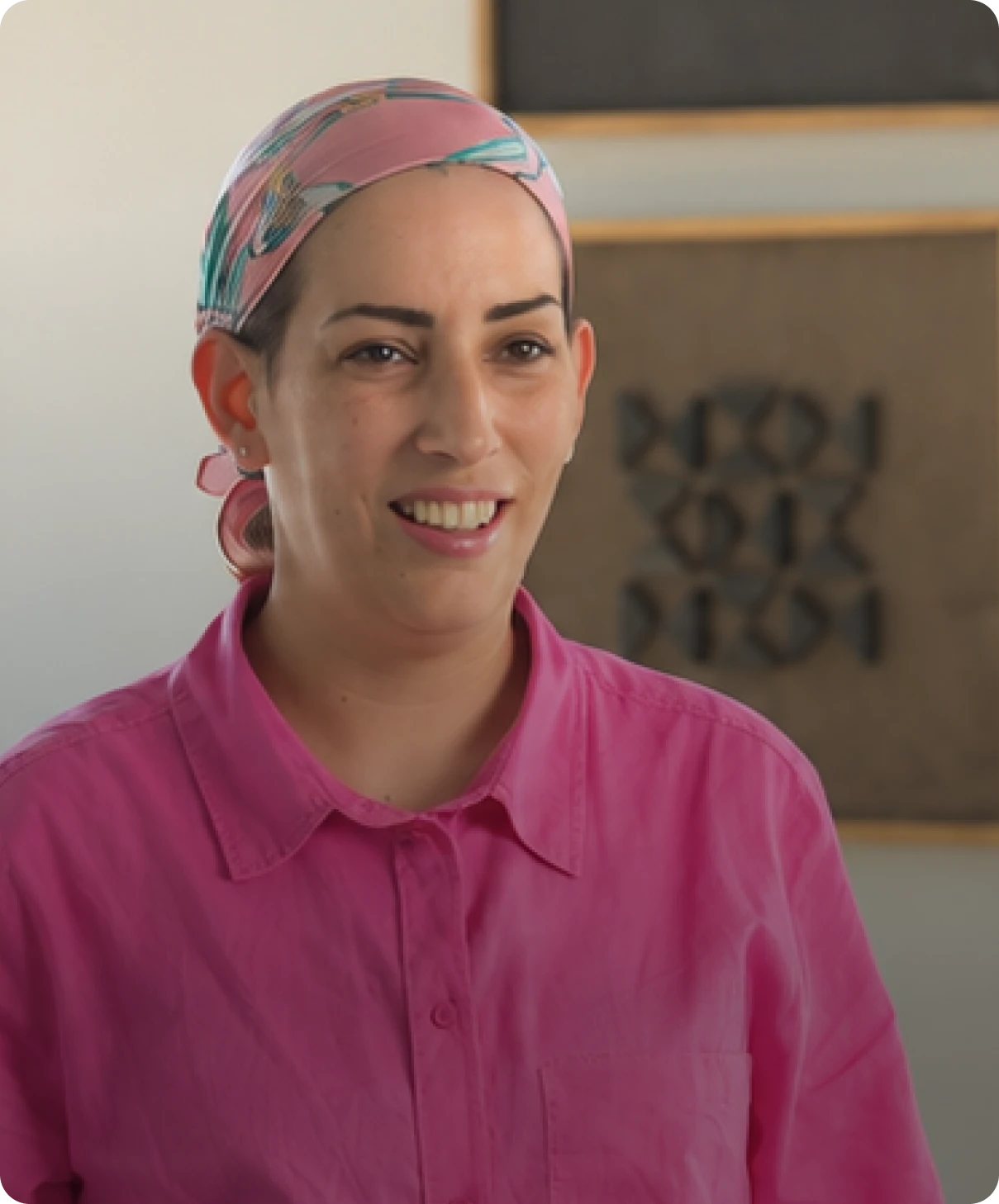 תקריב דיוקן של אישה מחייכת עם כיסוי ראש וחיצה ורודה, כחלק מהמלצות הלקוחות של Take It.